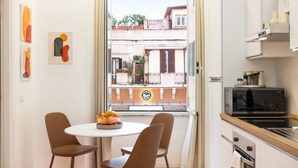 A modern kitchen with a dining area, a view of the street, and a balcony. - Rental in Rome Vic House (Rome)