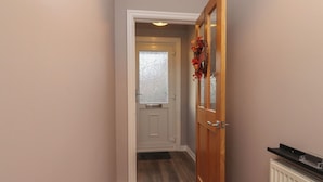 A hallway with a wooden door, a white door with frosted glass, and a radiator on the right. - Seaside Serenity (Lytham St. Anne's)