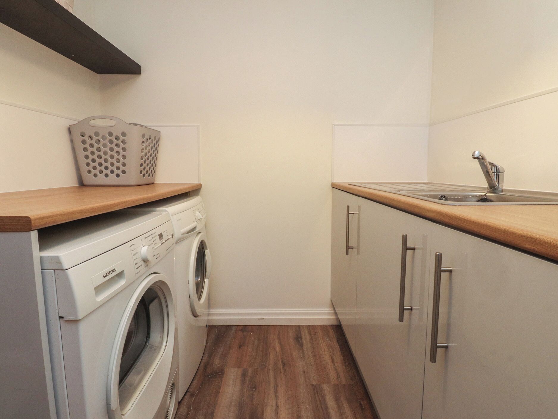 A compact laundry room with a washing machine, a drying rack, and a sink.