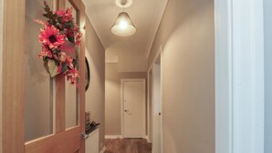 A hallway with wooden flooring, a white door at the end, and a light fixture on the ceiling. - Seaside Serenity (Lytham St. Anne's)