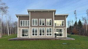 Ein modernes, zweistöckiges Haus mit flachem Dach, großen Fenstern und einer Steinfassade.