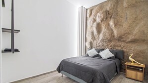 Et moderne soveværelse med en stor seng, et trænatbord og en væg med struktur.