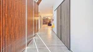 Un couloir moderne avec un lambris en bois d’un côté et une armoire grise de l’autre.