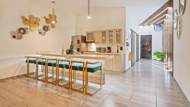 Une cuisine moderne dotée d’un îlot central, de meubles en bois et d’un coin repas avec une table et des chaises en verre.