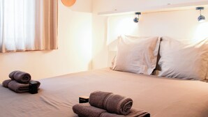 Ein ordentlich bezogenes Bett mit zwei Kissen, einem zusammengerollten Handtuch und einem Willkommen-Schild darauf.