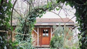 Ein Holzhaus mit einer sichtbaren Haustür und einem Weg, der davor führt, umgeben von üppiger Vegetation.