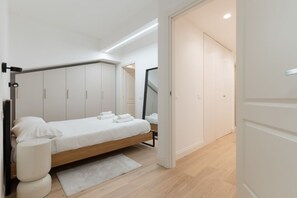 A modern bedroom with a bed, bedside tables, and a wardrobe. - GuestHost - Modern and spacious 96 sqm apartment for 4 guests, located on the semi-basement level of a residential building (stairs to access).The property is just 200 meters from the “De Angeli” M1 Red Line, offering a direct connection to the Duomo (Milan)