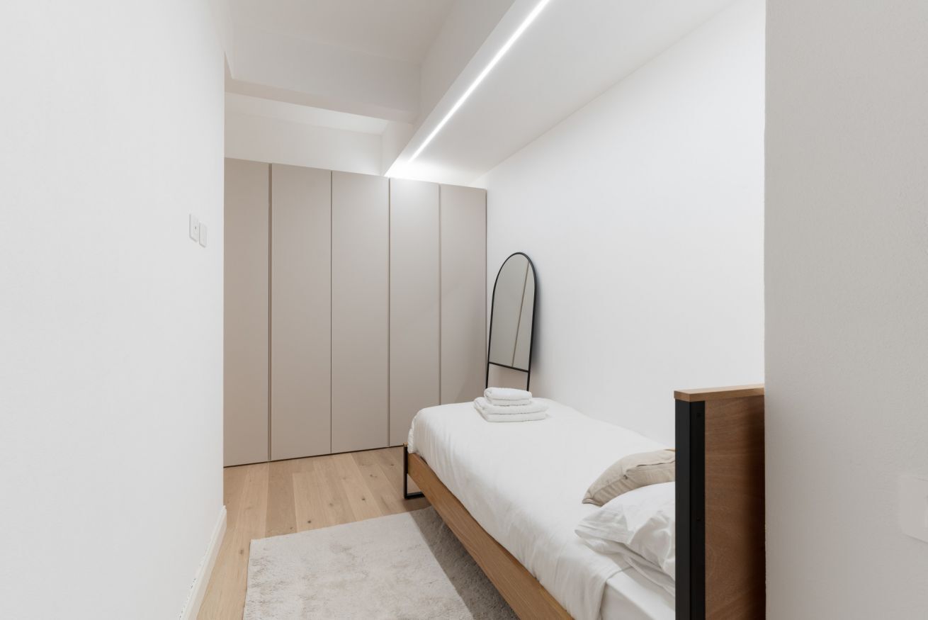 Une chambre à coucher au style minimaliste, avec un lit, un miroir et une armoire.
