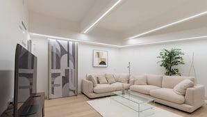 Ein modernes Wohnzimmer mit einer Couch, einem Glastisch und einem Fernseher.