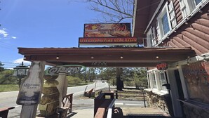 A restaurant with a 'Breakfast All Day' sign, outdoor seating, and a 'Corona Extra' beer bottle. - Country Lodge (Big Bear Lake)