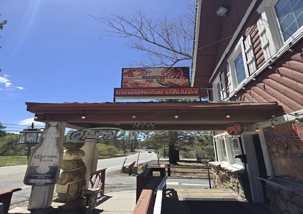 A restaurant with a 'Breakfast All Day' sign, outdoor seating, and a 'Corona Extra' beer bottle. - Country Lodge (Big Bear Lake)