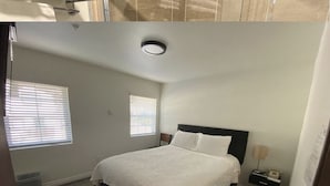 A bedroom with a bed, two bedside tables, a nightstand, a window, and a ceiling light. - Country Lodge (Big Bear Lake)