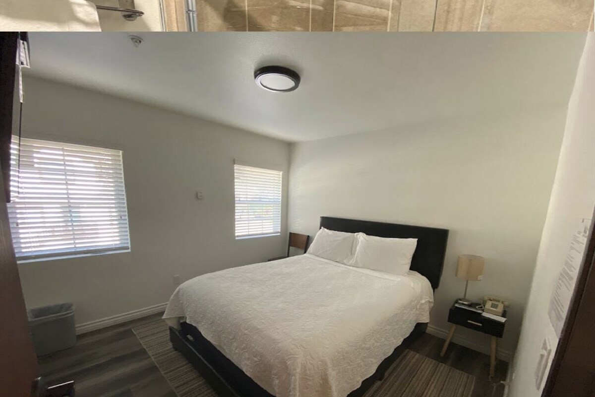 A bedroom with a bed, two bedside tables, a nightstand, a window, and a ceiling light.