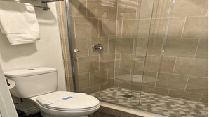 A bathroom with a toilet, shower, and tiled floor. - Country Lodge (Big Bear Lake)