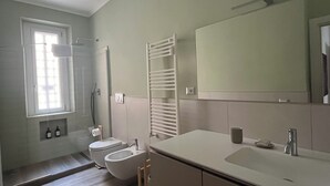 Un baño moderno con inodoro, bidé, lavabo y un espejo grande.