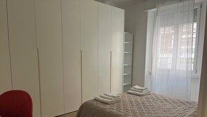 Un dormitorio con una cama, una silla roja y un armario.