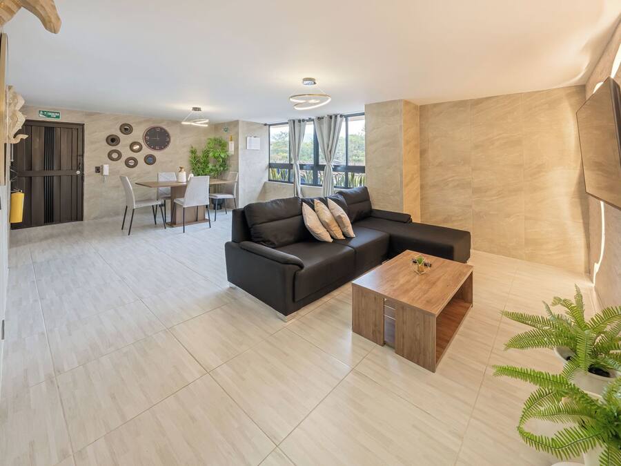 Uma sala de estar moderna com um sofá seccional, uma mesa de centro de madeira e uma área de jantar com mesa e cadeiras.