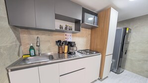 Una cucina moderna con mobili grigi, un lavello in acciaio inossidabile, una macchina da caffè e un forno a microonde integrato.