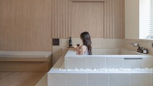 Un baño moderno con una bañera, un banco y un estante con artículos de aseo.