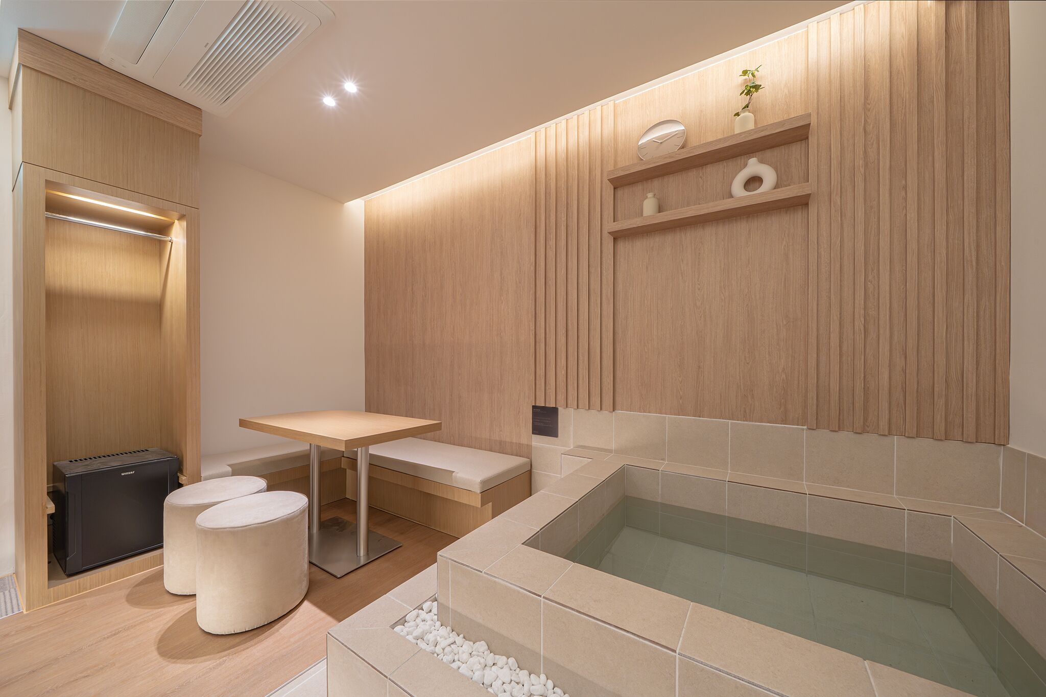 Un baño moderno con un tocador de madera, una bañera y una pequeña mesa con taburetes.