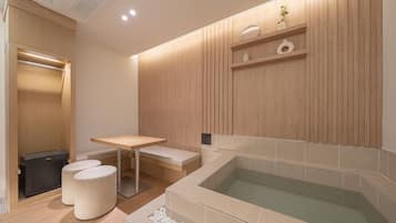 Un baño moderno con un tocador de madera, una bañera y una pequeña mesa con taburetes.