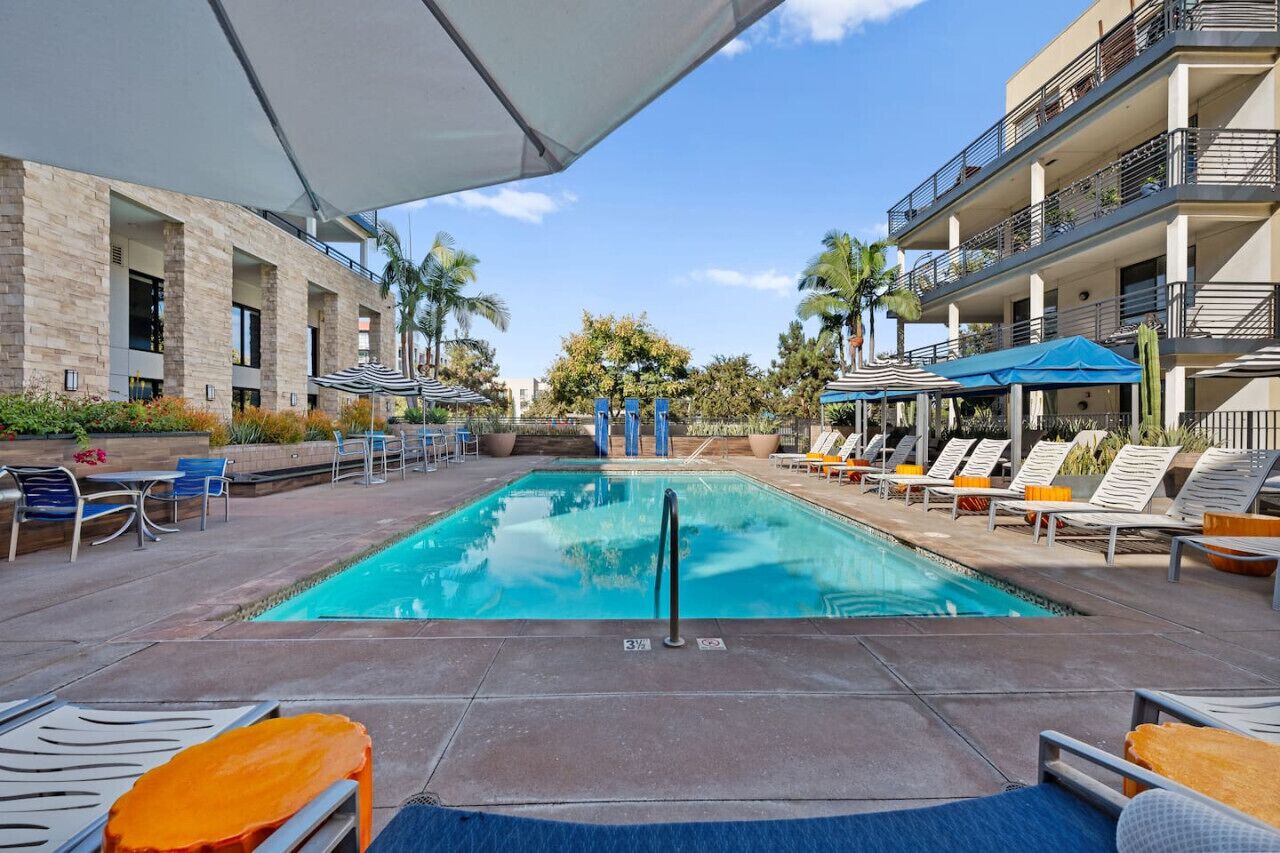 A pool area with lounge chairs, umbrellas, and a clear blue pool.