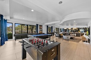 Un espacio interior amplio con mesa de futbolín, mesa de billar y zona de bar.