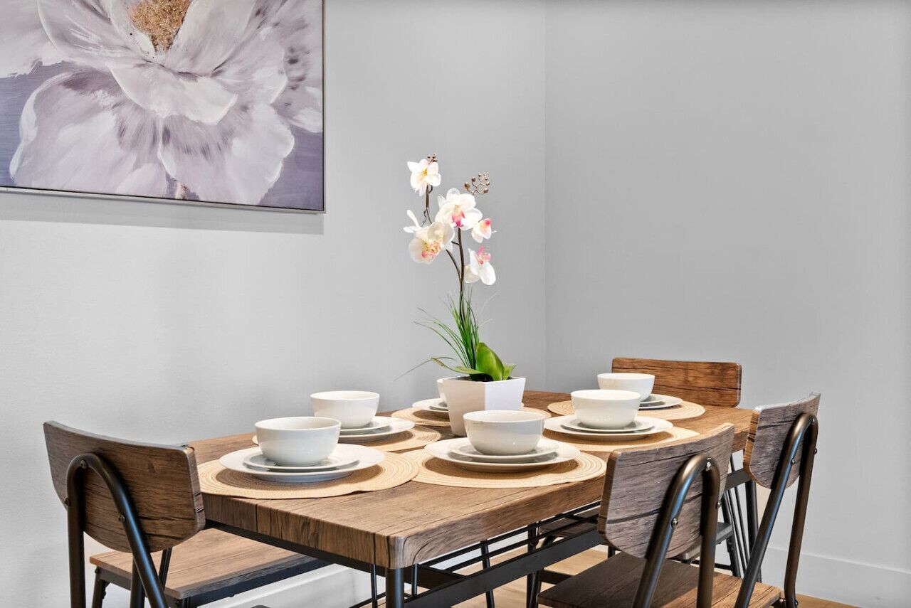 A dining table with white bowls and plates, surrounded by wooden chairs.