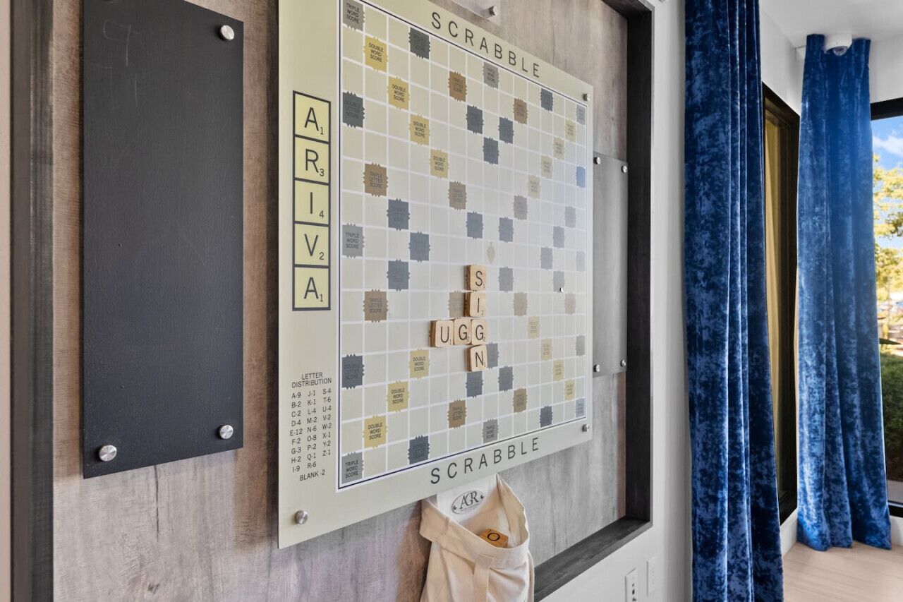 Um jogo de Scrabble com peças na parede, uma lousa com letras e uma janela com cortinas azuis.