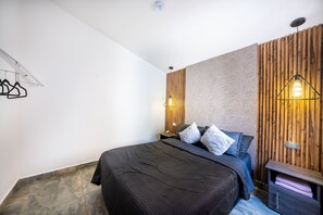 Quarto moderno com cama, mesas de cabeceira, luminária pendente e uma parede de destaque em madeira.