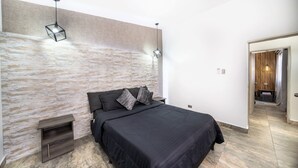 Ein modernes Schlafzimmer mit einem großen Bett, einer Wand mit Steinoptik und einem Nachttisch aus Holz.