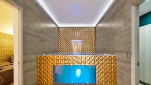 Ein modernes Badezimmer mit Wand in geometrischem Muster, einem integrierten Waschbecken und einem Flachbildfernseher.
