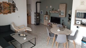 Een moderne woonkamer met een bank, een salontafel, een televisie en een eethoek met stoelen en een tafel.