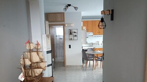 Een moderne keuken met houten kastjes, een eethoek met tafel en stoelen, en een gang naar een deur.