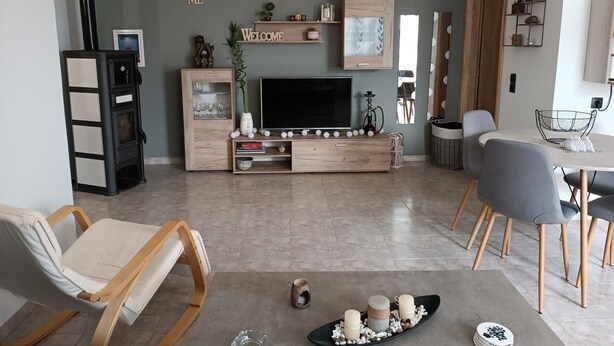 Een moderne woonkamer met een televisie, een houten entertainmentkast en een zithoek.