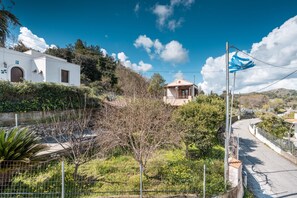 A white building with a red door, a small balcony, and a clear blue sky. - Traditional Thea Home, Rhodes (Ρόδος)