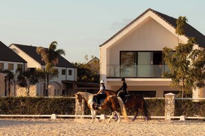 Ein modernes Haus mit einem Balkon, einem Pferd und Reitern.