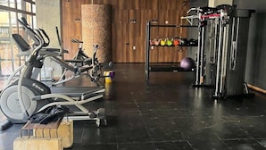 Ett gym med träningsutrustning, en väggpanel av trä och ett ställ med vikter.