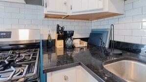Een moderne keuken met witte kasten, een zwart aanrecht, een roestvrijstalen spoelbak en een gasfornuis.