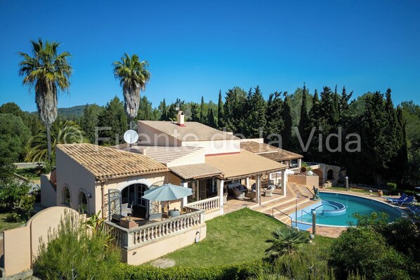 Een villa in mediterrane stijl met een zwembad, terras en weelderige beplanting.