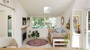 Ein gemütliches Zimmer mit einem Bett, einem Kamin, einem Fenster mit Pflanzen und einem Deckenventilator.