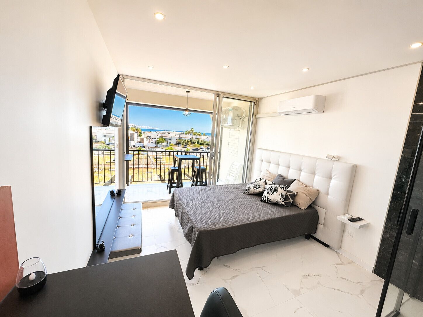 Et moderne soveværelse med seng, skrivebord og balkon med udsigt.