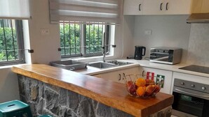 Een moderne keuken met een stenen keukeneiland, barstoelen, een broodrooster en een spoelbak.