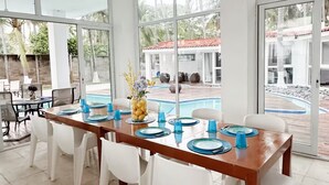 A dining area with a long table set for six, white chairs, and blue glassware. - Costa del Sol Beach, El Salvador / Residencia del sol (La Paz)