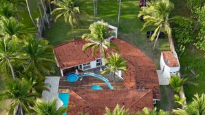 An aerial view of a resort with multiple buildings, a swimming pool, and numerous palm trees. - Costa del Sol Beach, El Salvador / Residencia del sol (La Paz)