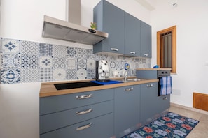 Eine moderne Küche mit gemusterten Fliesen, einer Kaffeemaschine und einer blauen Arbeitsplatte.