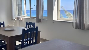 A room with large windows, a dining table, and blue chairs. - Apartment 'Bellavista Sul Mare' with Sea View, Wi-Fi and Air Conditioning (Palermo)