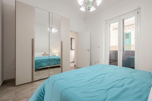 Ein Schlafzimmer mit einem Bett, einem Kleiderschrank und einer Tür zu einem Balkon.