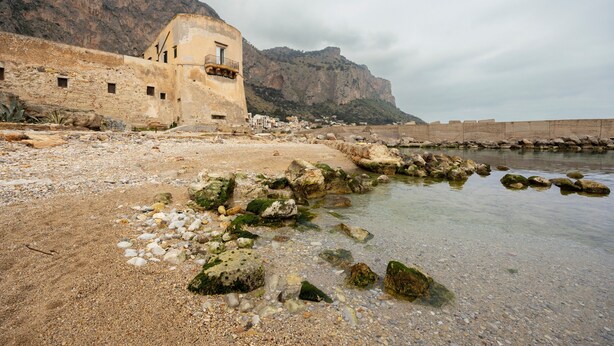 A coastal building with a balcony, a rocky shoreline, and a mountainous backdrop. - Apartment 'Bellavista Sul Mare' with Sea View, Wi-Fi and Air Conditioning (Palermo)