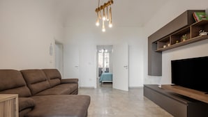 A modern living room with a brown sofa, a flat-screen TV, and a wooden shelf. - Apartment 'Bellavista Sul Mare' with Sea View, Wi-Fi and Air Conditioning (Palermo)